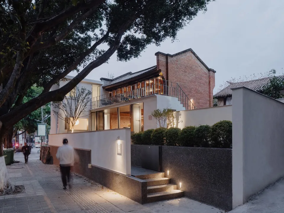 A modern house with a large white wall, a black staircase, and a brick exterior, set in a calm and serene environment