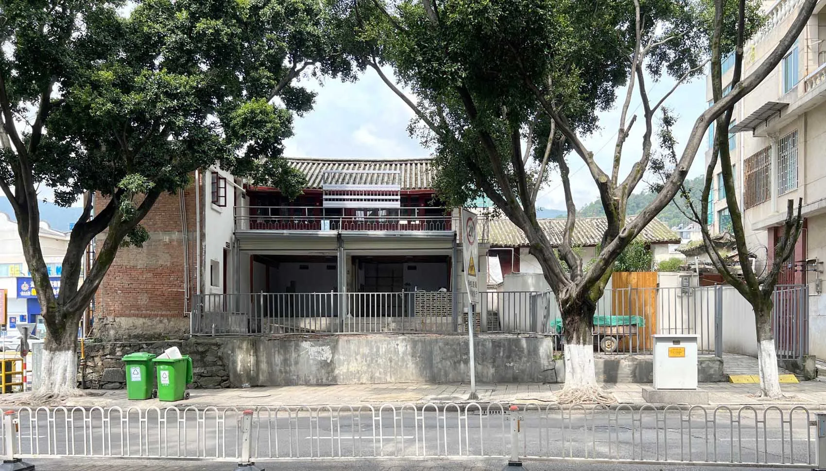 A traditional building with a brick facade and outdoor seating area, surrounded by a tree and a parked truck