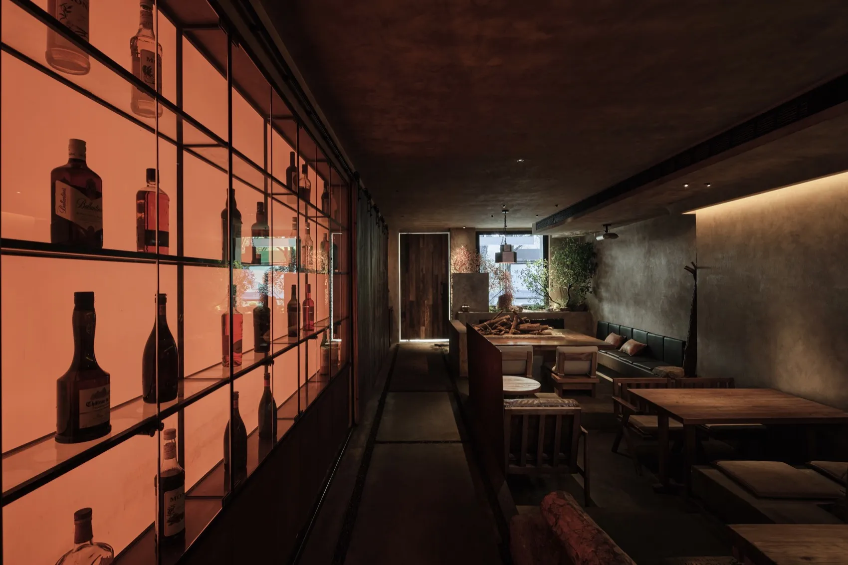 A sophisticated bar area with wine bottles, chairs, and potted plants, creating a warm and inviting atmosphere