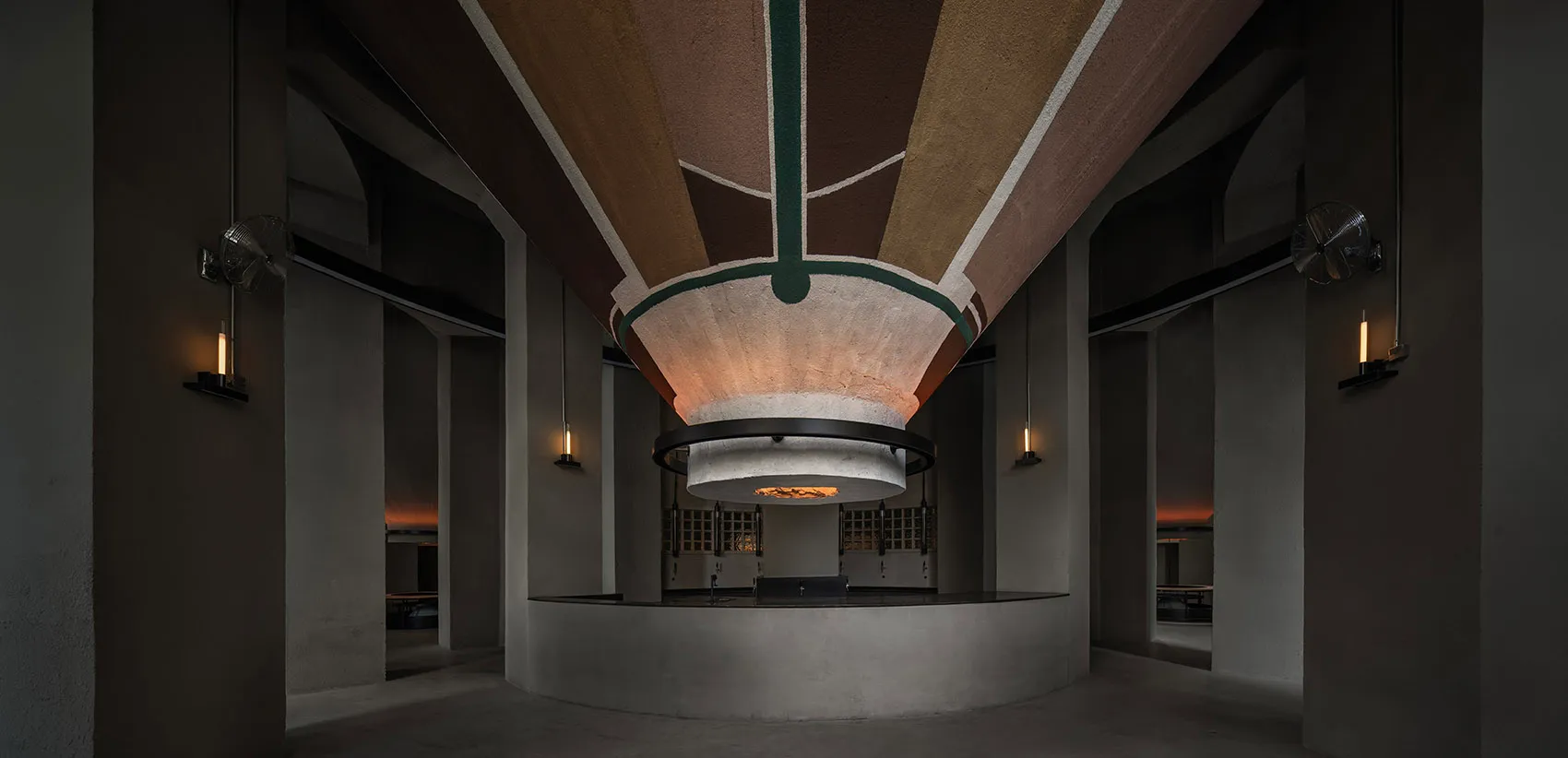 Modern lobby with a circular structure, concrete walls, wooden elements, and warm lighting