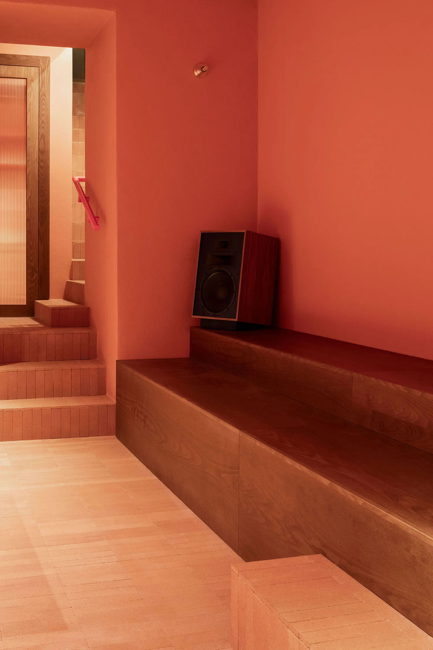 Warm and inviting orange room with wooden floors and walls, featuring two benches and a speaker system