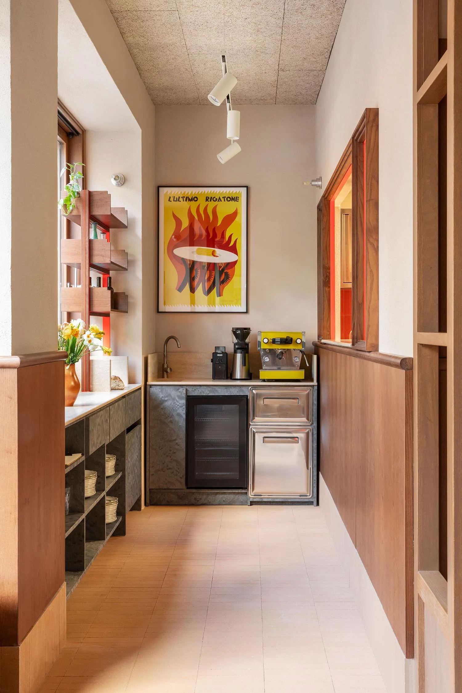 Modern kitchen with a sink, oven, and refrigerator, featuring two potted plants and a well-lit atmosphere