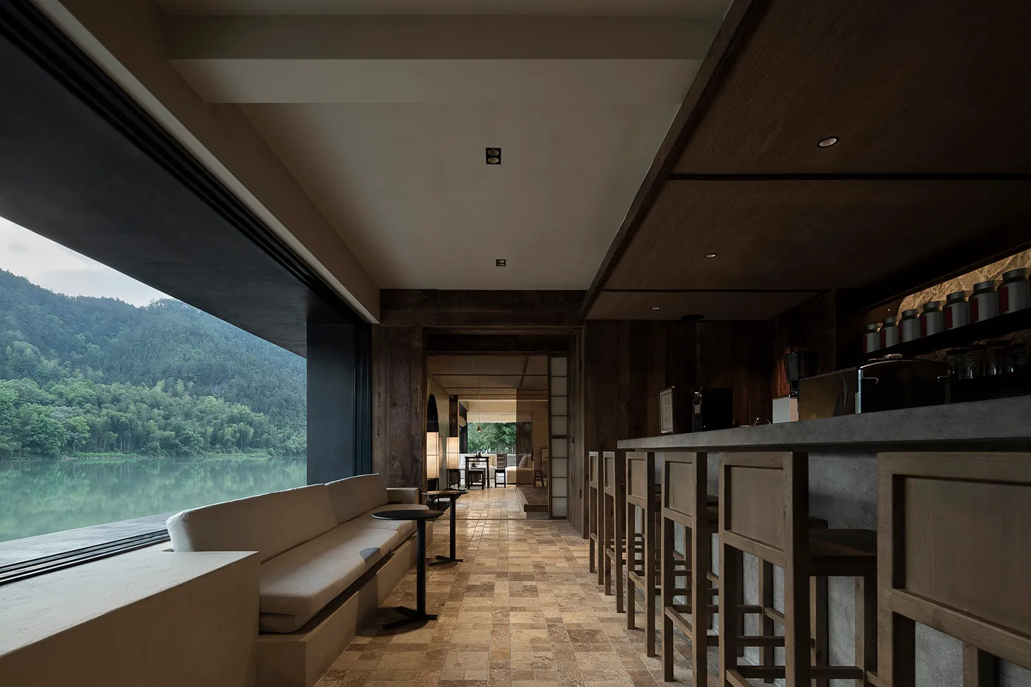 A bar area with stools and chairs, surrounded by dining tables in a stylish restaurant setting