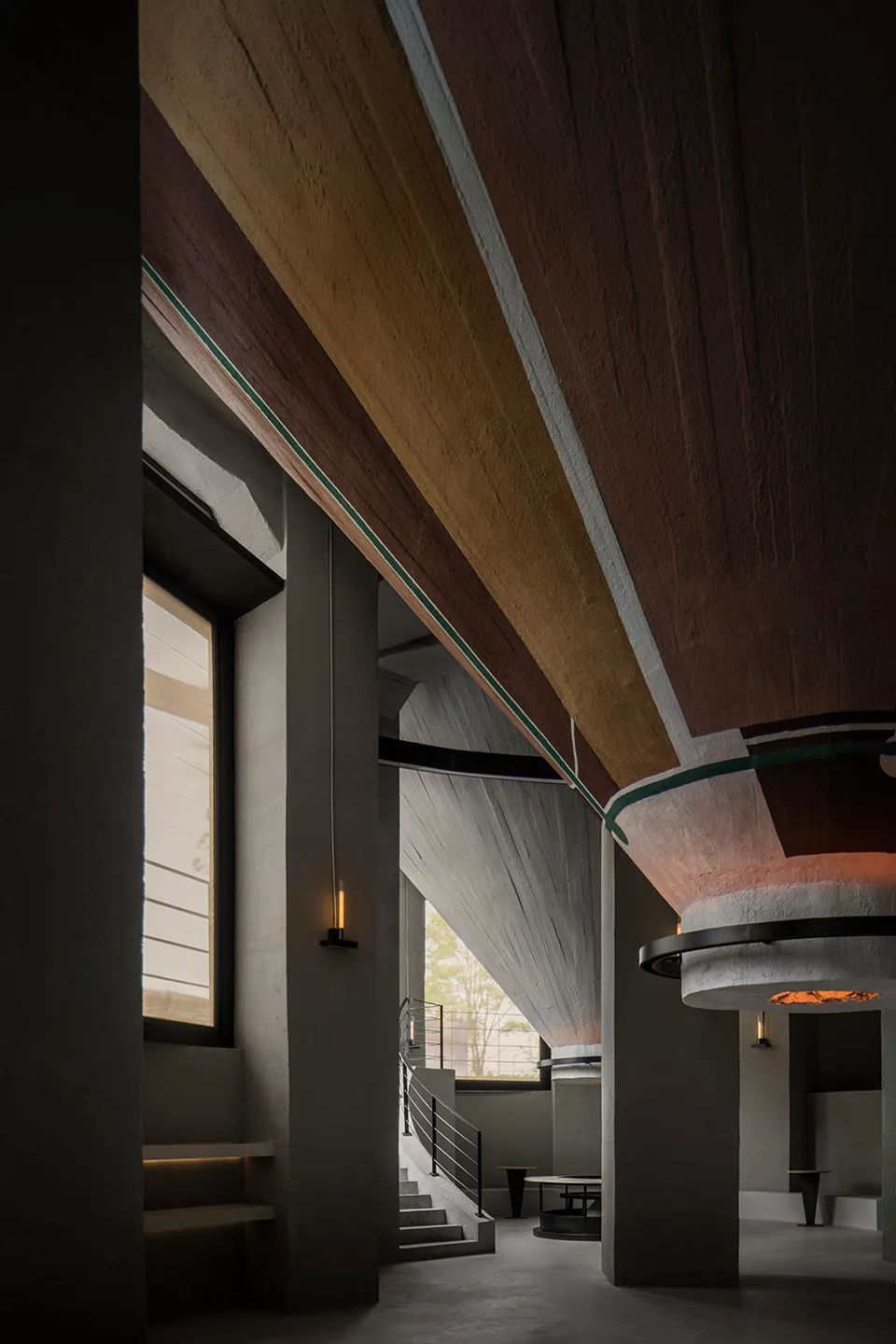 A dimly lit interior space with a metal staircase and a nearby window