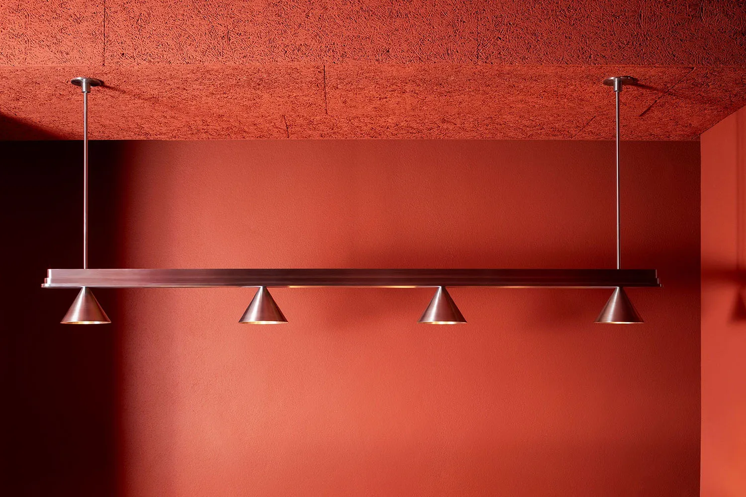 A warm and inviting room with an orange wall, brick texture, and soft lighting from hanging silver fixtures
