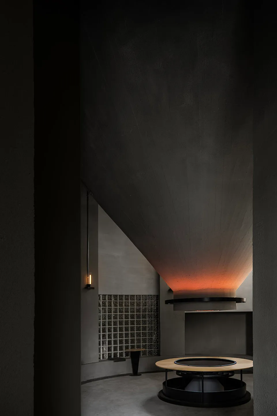 Dark hallway with a gray-painted wall, black tile floor, and a staircase in the background, featuring a sink near the center