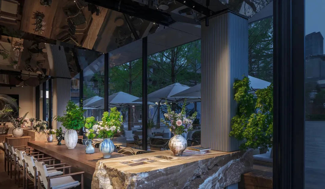 Elegant dining space with a stone countertop, vases, umbrellas, and natural elements, designed for socializing or dining