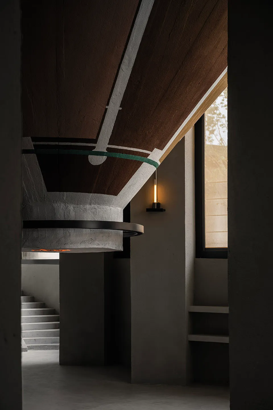 A modern lobby with a circular structure, concrete walls, a wooden dome ceiling, and a light fixture