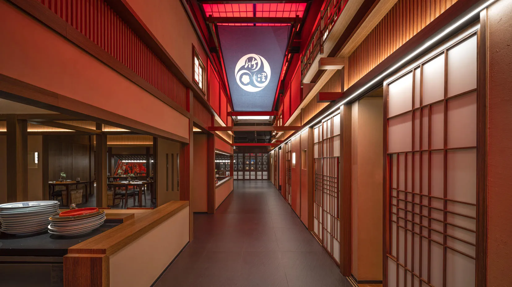 Elegant Asian restaurant with red walls, wooden floors, and a black and white tiled hallway with several doors leading to various rooms