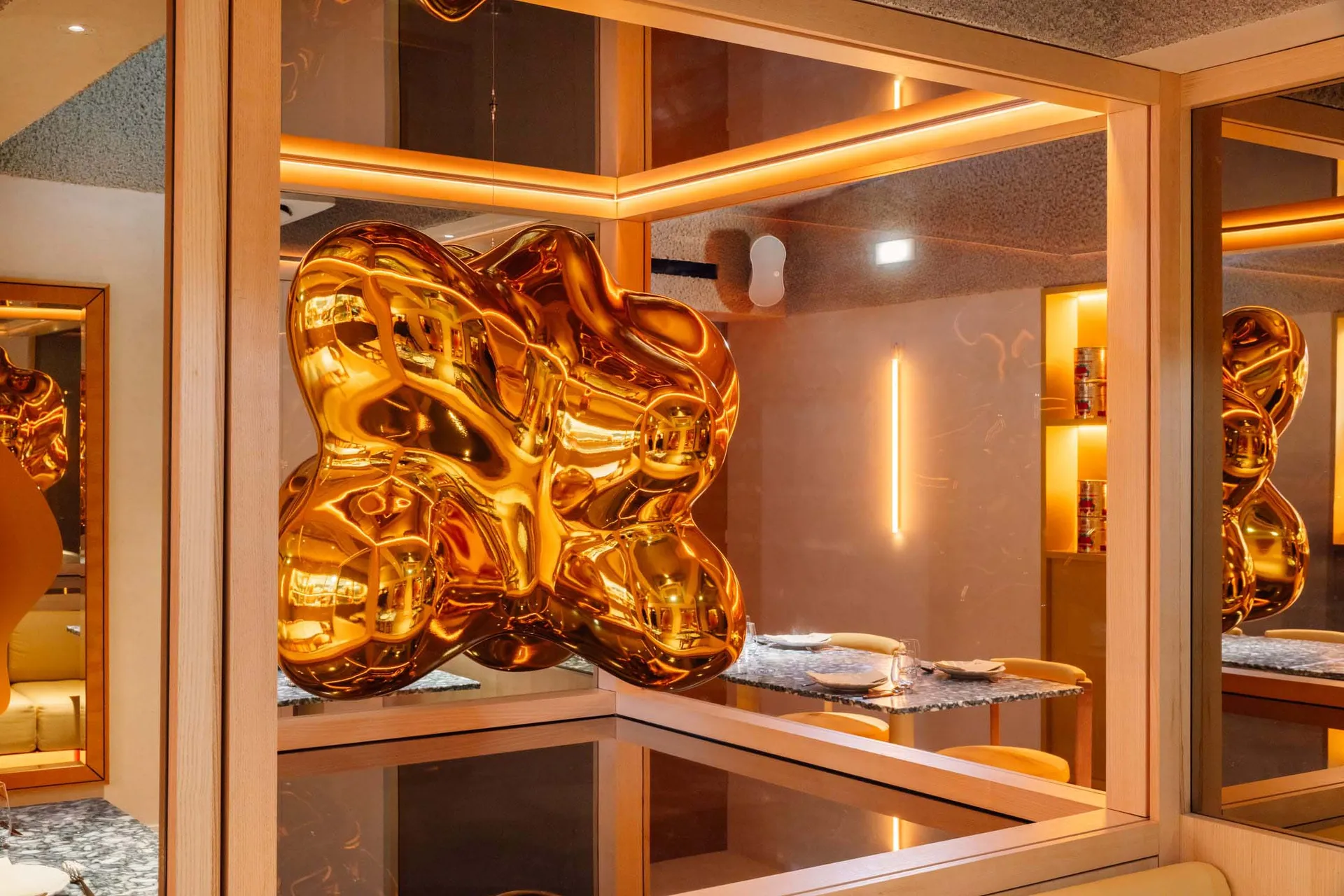 Elegant showroom with a gold metal sculpture, chairs, and decorative bottles, set against a sophisticated backdrop