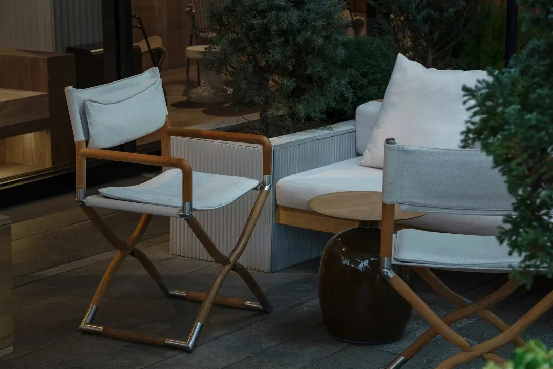 An inviting outdoor patio with stone flooring, two chairs, and two couches, set in a well-lit and comfortable atmosphere