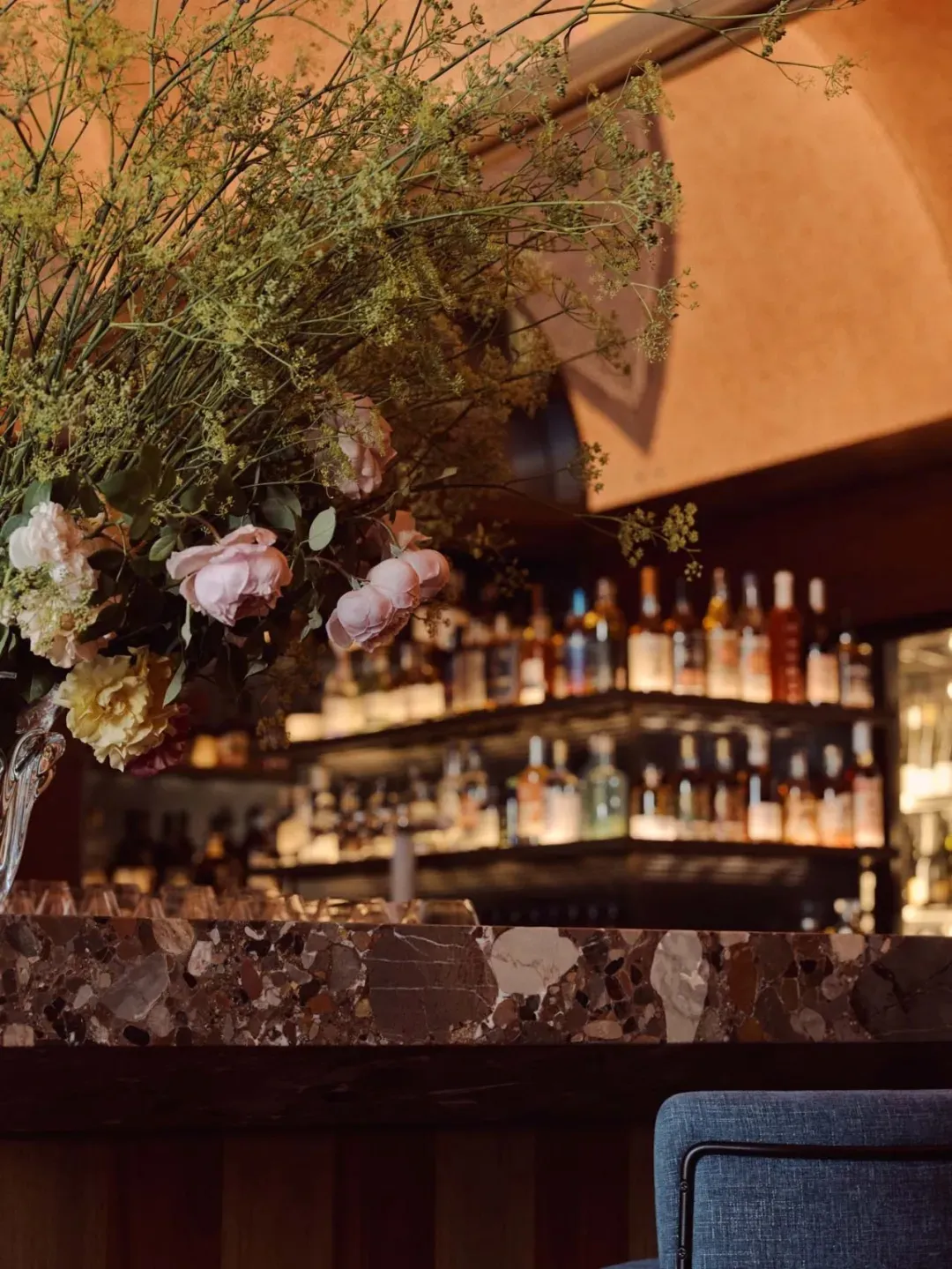 A cozy bar scene with a counter, flowers, and bottles, creating an inviting atmosphere