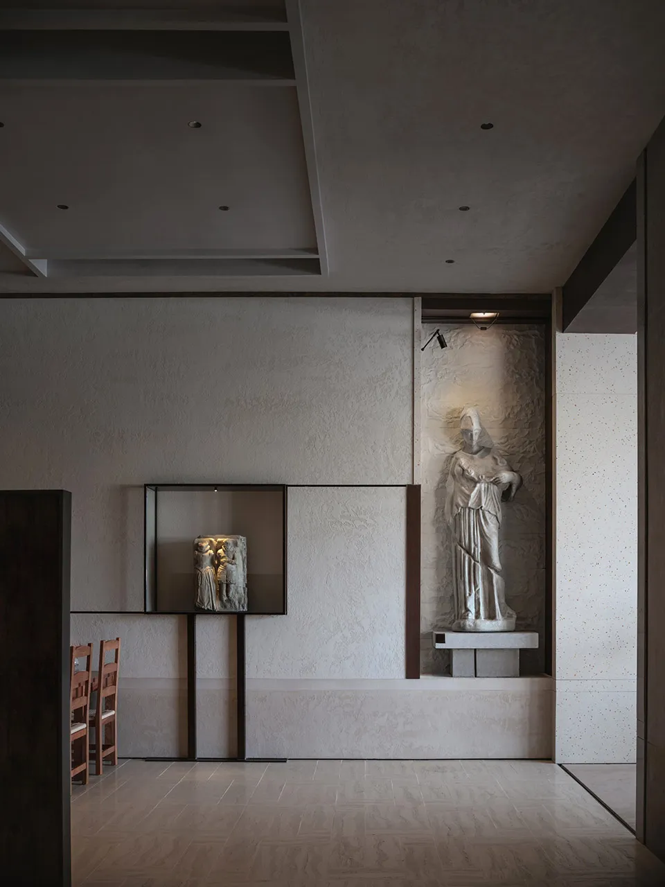A calm art gallery space with a statue of a woman surrounded by paintings and chairs for visitors to sit and admire the artwork