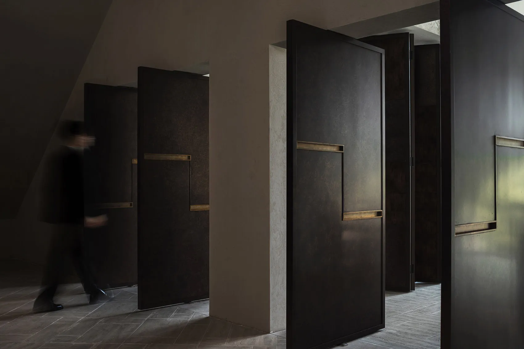 A dimly lit hallway with wooden doors featuring gold handles and stone walls, creating a mysterious atmosphere