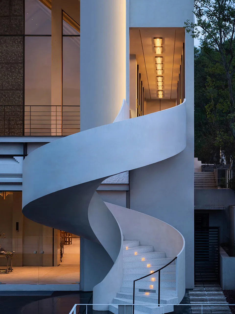 A modern building with a spiral staircase made of white marble, featuring clean lines and minimalistic design elements, well-lit by natural and artificial light