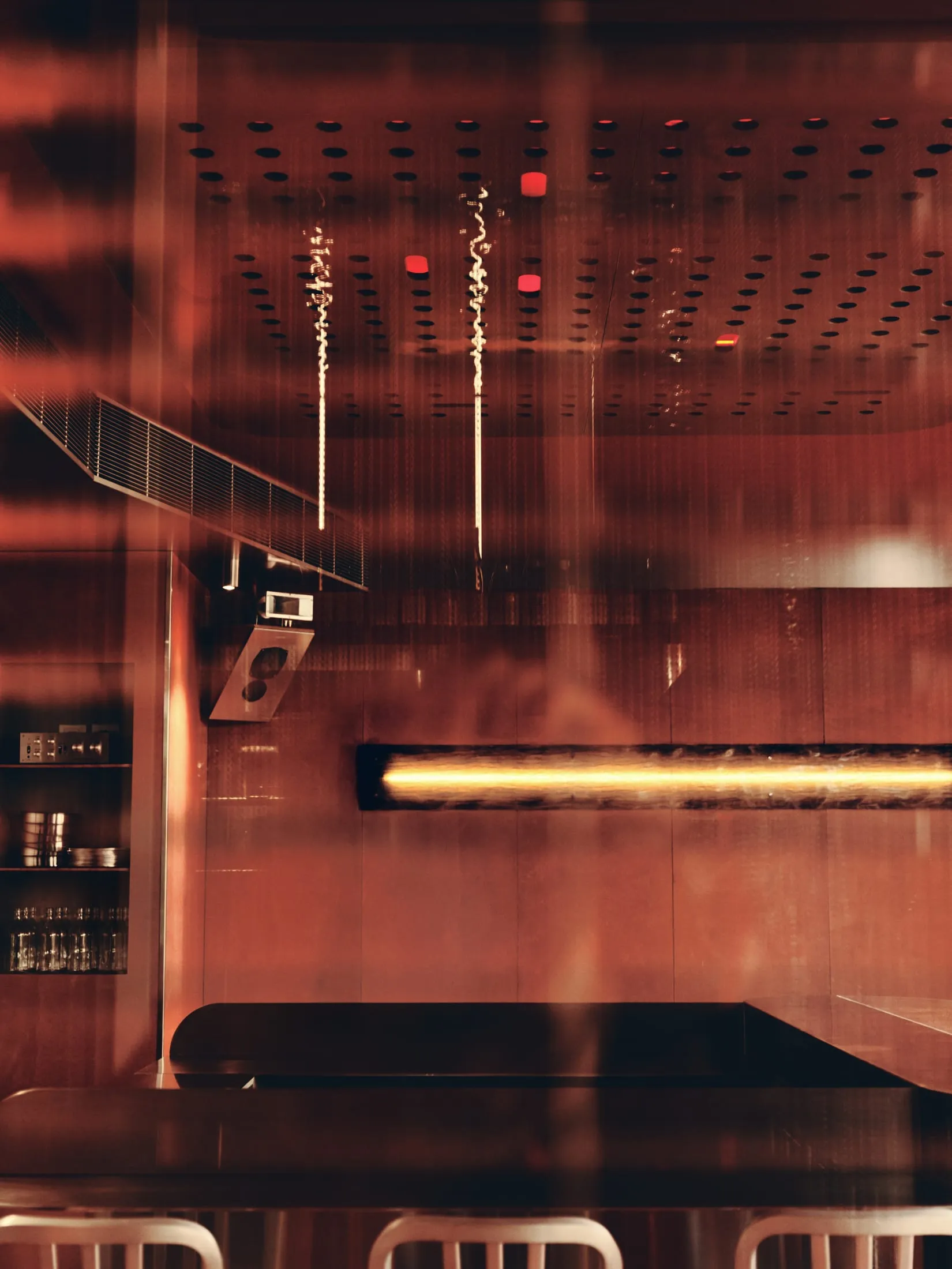 A well-lit kitchen with a red accent wall, black countertop, and decorative bottles, creating a warm atmosphere