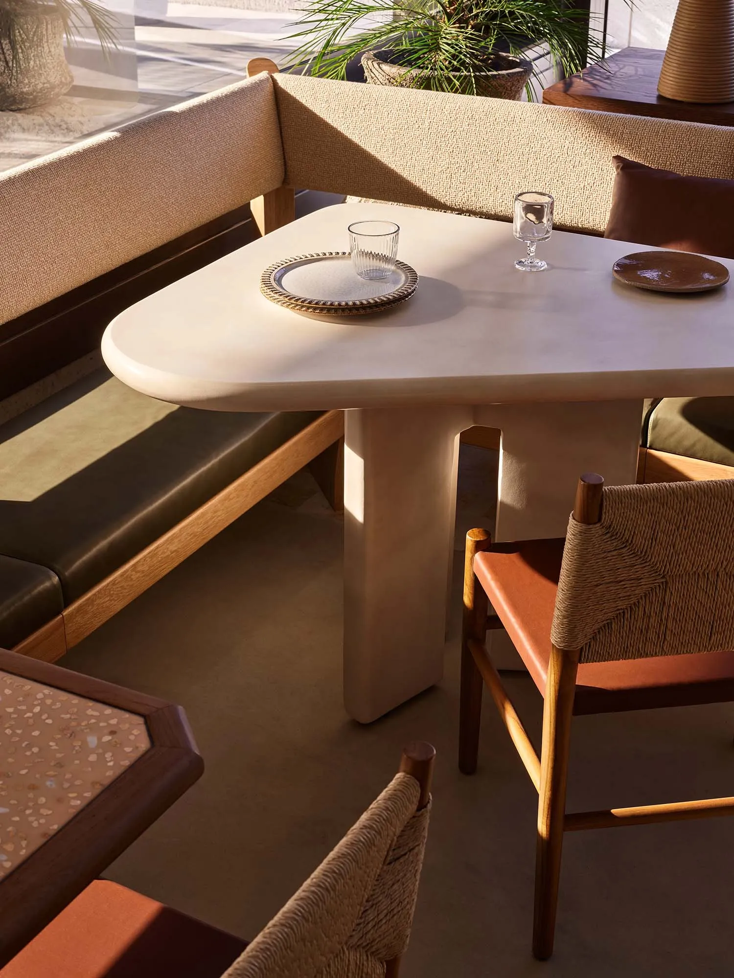 A modern dining area with a large white table surrounded by multiple chairs, set up for a meal in a clean and inviting environment