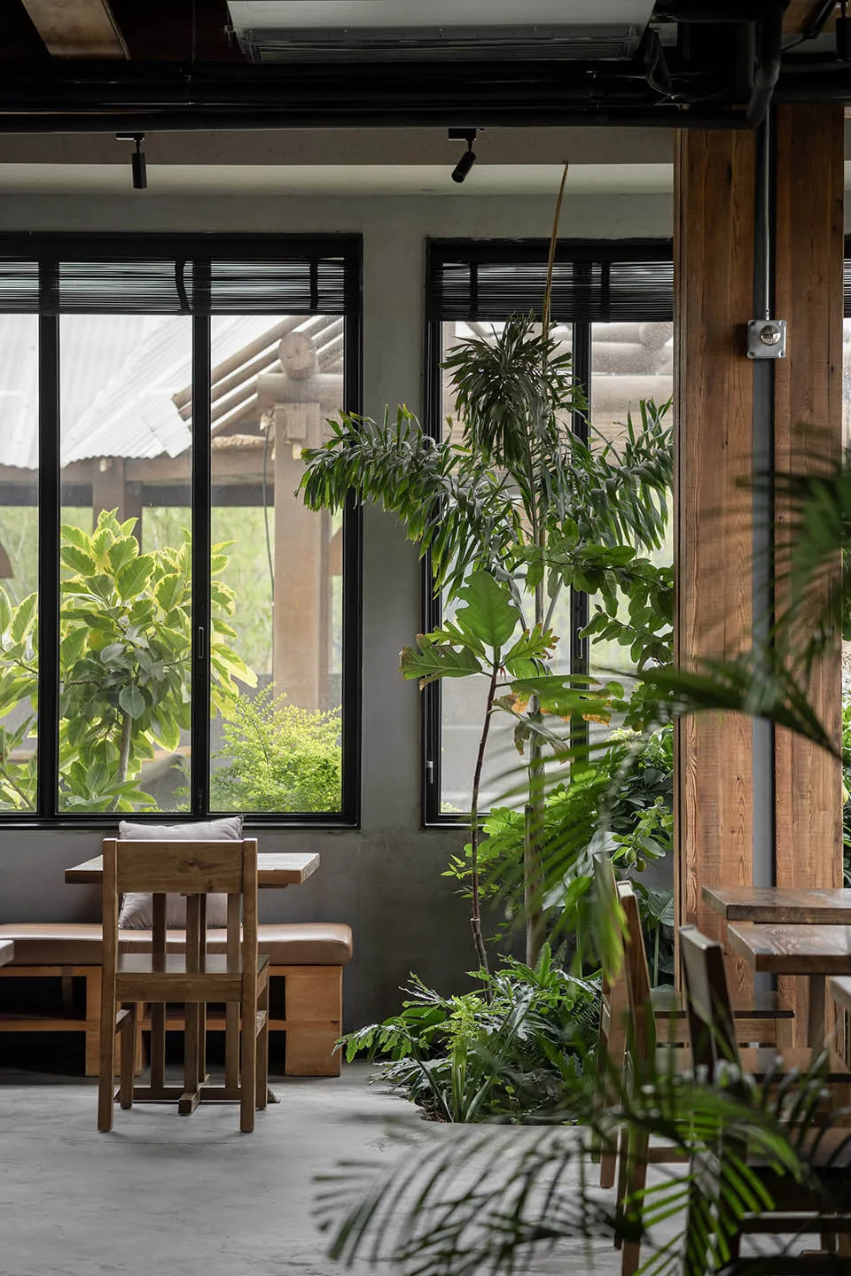 A modern restaurant interior with wooden tables and chairs, multiple dining tables, and benches, creating a warm and inviting atmosphere