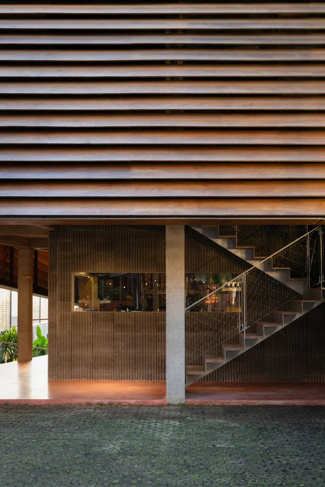 A brown building with a wooden staircase and metal railing, featuring a potted plant and a sense of depth and structure