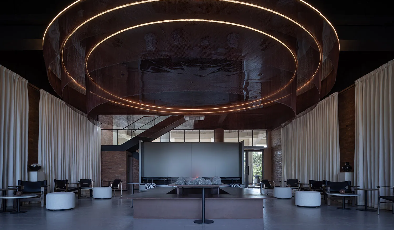 Elegant hotel lobby with a large circular table, multiple couches, and a wooden ceiling