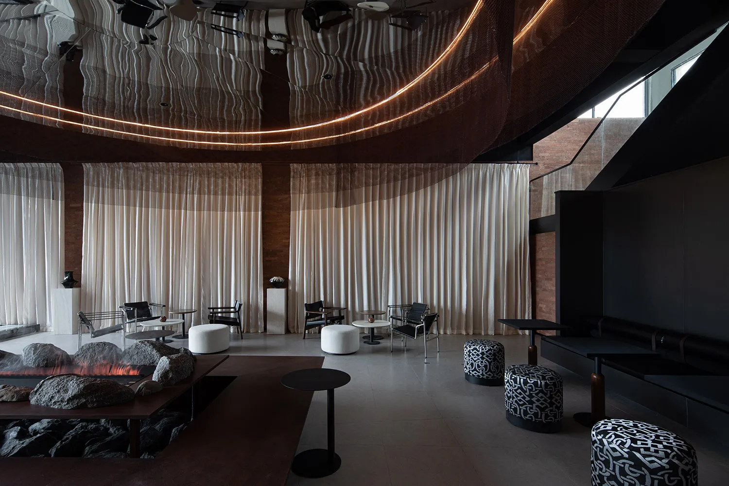Comfortable modern dining space with a large table, couches, and a fireplace, surrounded by warm lighting