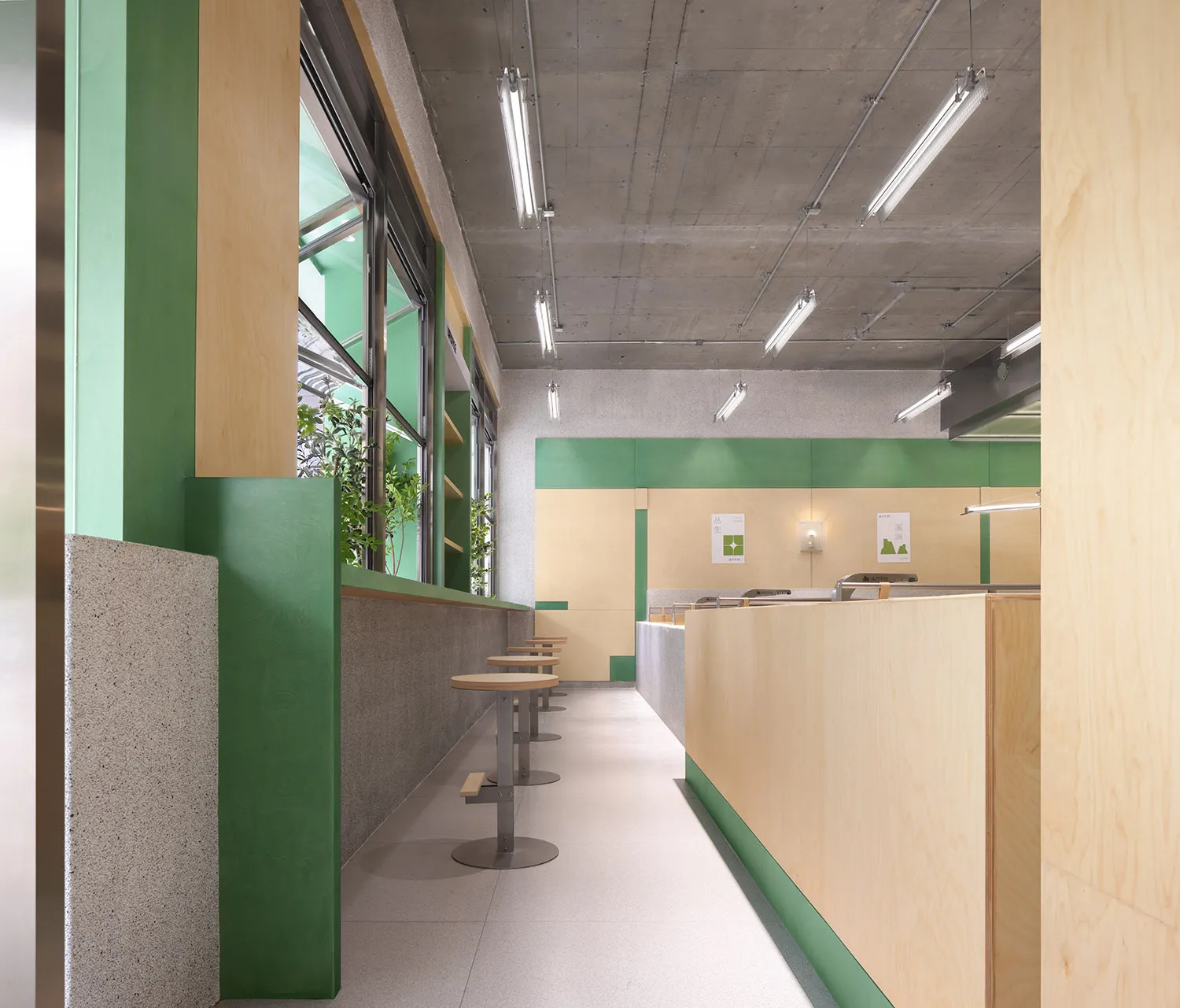 Empty restaurant interior with green walls and flooring, featuring chairs placed throughout the space in a clean and well-organized atmosphere