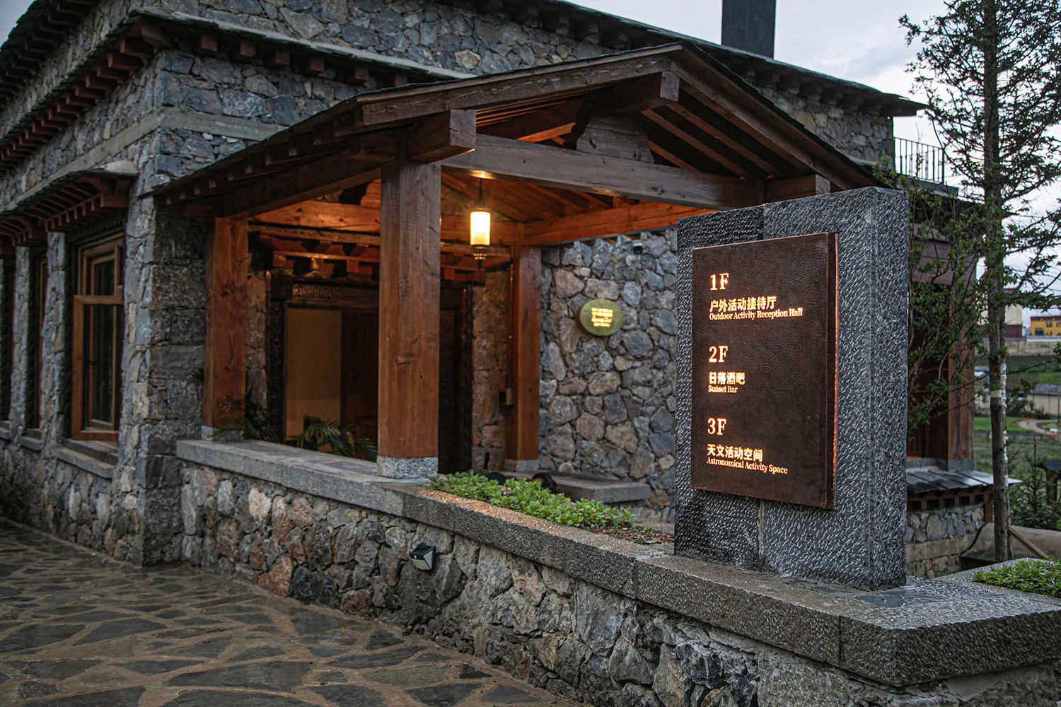 A stone building with a wooden structure and a large archway, featuring signs and a blend of traditional and modern architectural elements