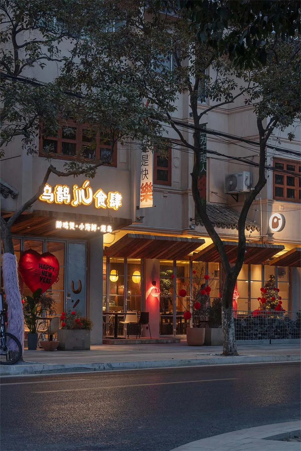 白色建築搭配紅色點綴，戶外座位區擺放盆栽植物，營造夜晚溫暖親切的氛圍