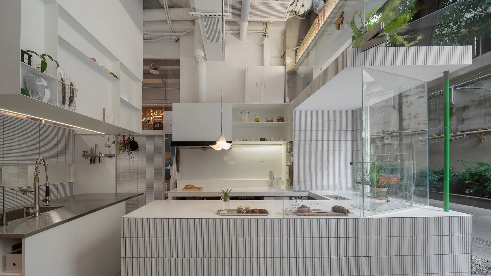 A clean and organized open kitchen space with white walls, tile flooring, and various kitchen items and objects placed throughout