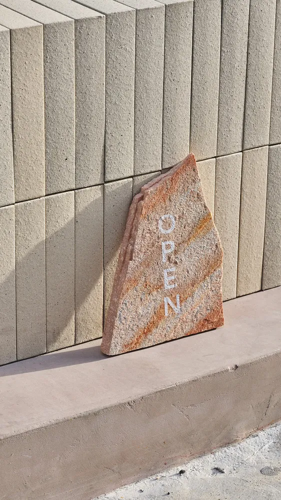 An outdoor entrance with a marble rock and a brick wall in the background