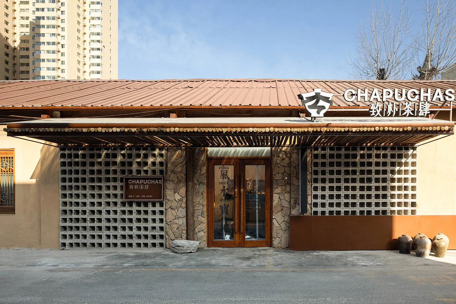 A modern Asian restaurant with a brown wooden exterior, featuring a large doorway and comfortable seating areas inside