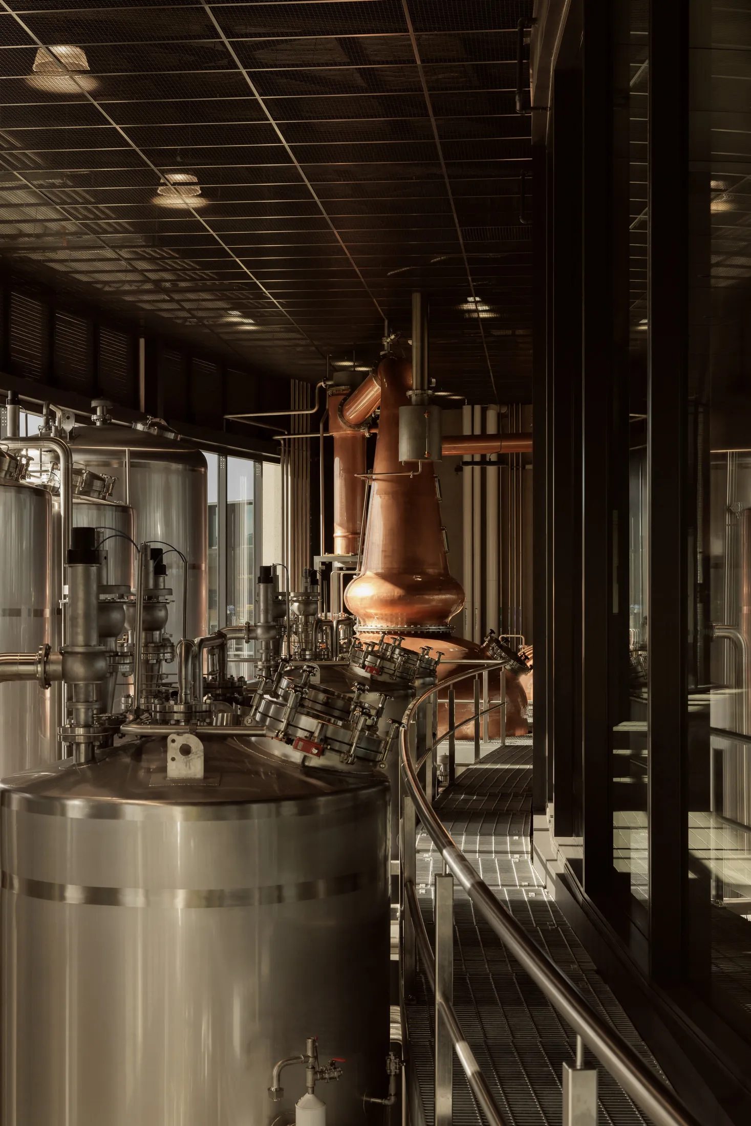 Industrial workspace with stainless steel equipment, pipes, and multiple tanks in a processing or storage area