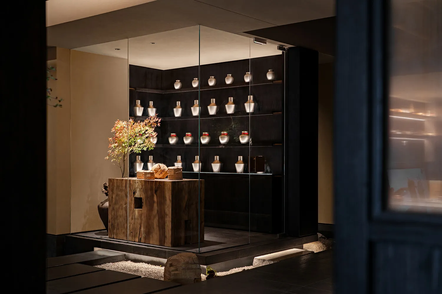 A large glass display case in an interior design showroom contains thirteen vases of various sizes and shapes, creating an elegant and sophisticated atmosphere
