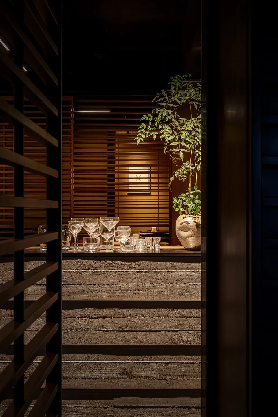 A cozy indoor space with a wooden bar area, wine glasses, and vases, creating a warm and inviting atmosphere for social gatherings