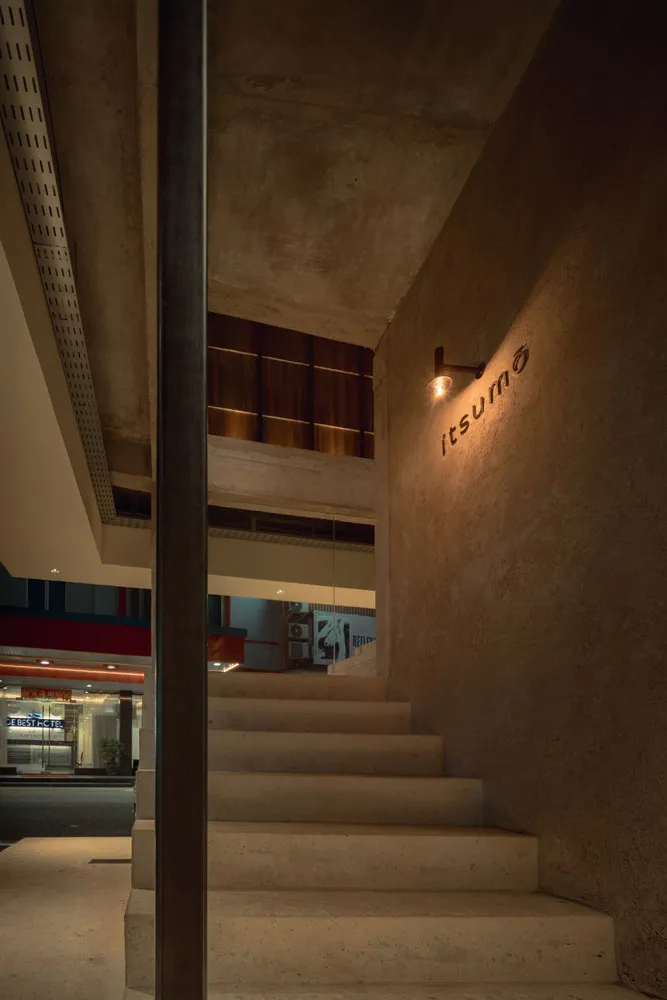 A well-lit staircase in a modern office building with concrete stairs, flanked by potted plants and conveying a sense of functionality and organization