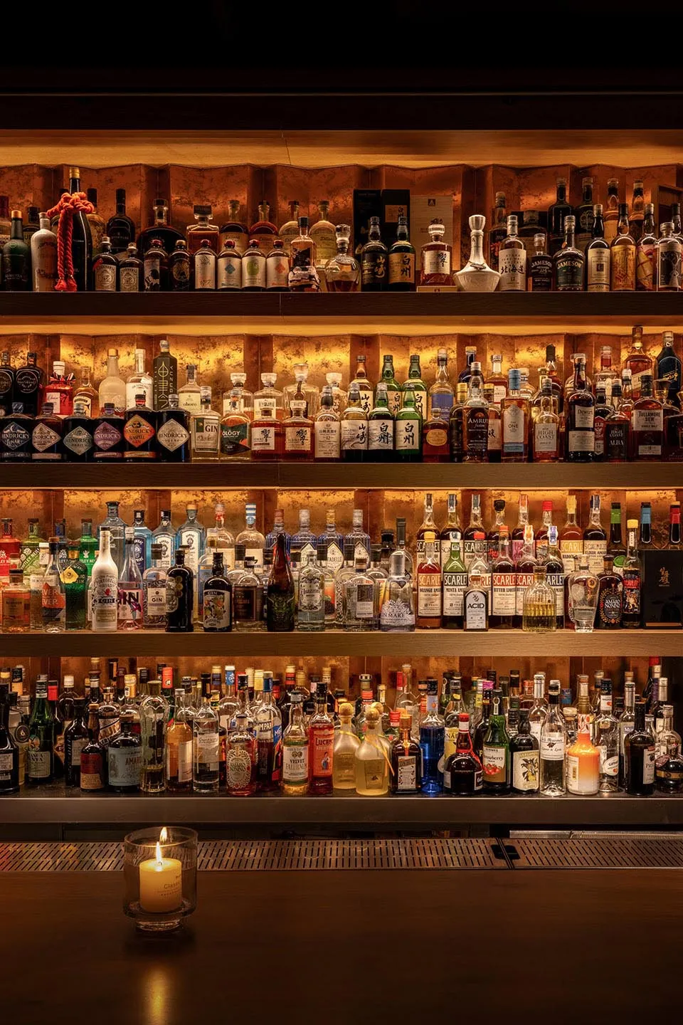 A bar area with wooden shelves displaying a collection of liquor bottles in a visually appealing arrangement, creating a warm and inviting atmosphere