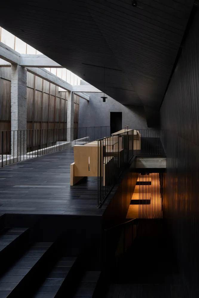 A dark interior space with a metal staircase, two benches, and a focus on the stairwell and its surroundings