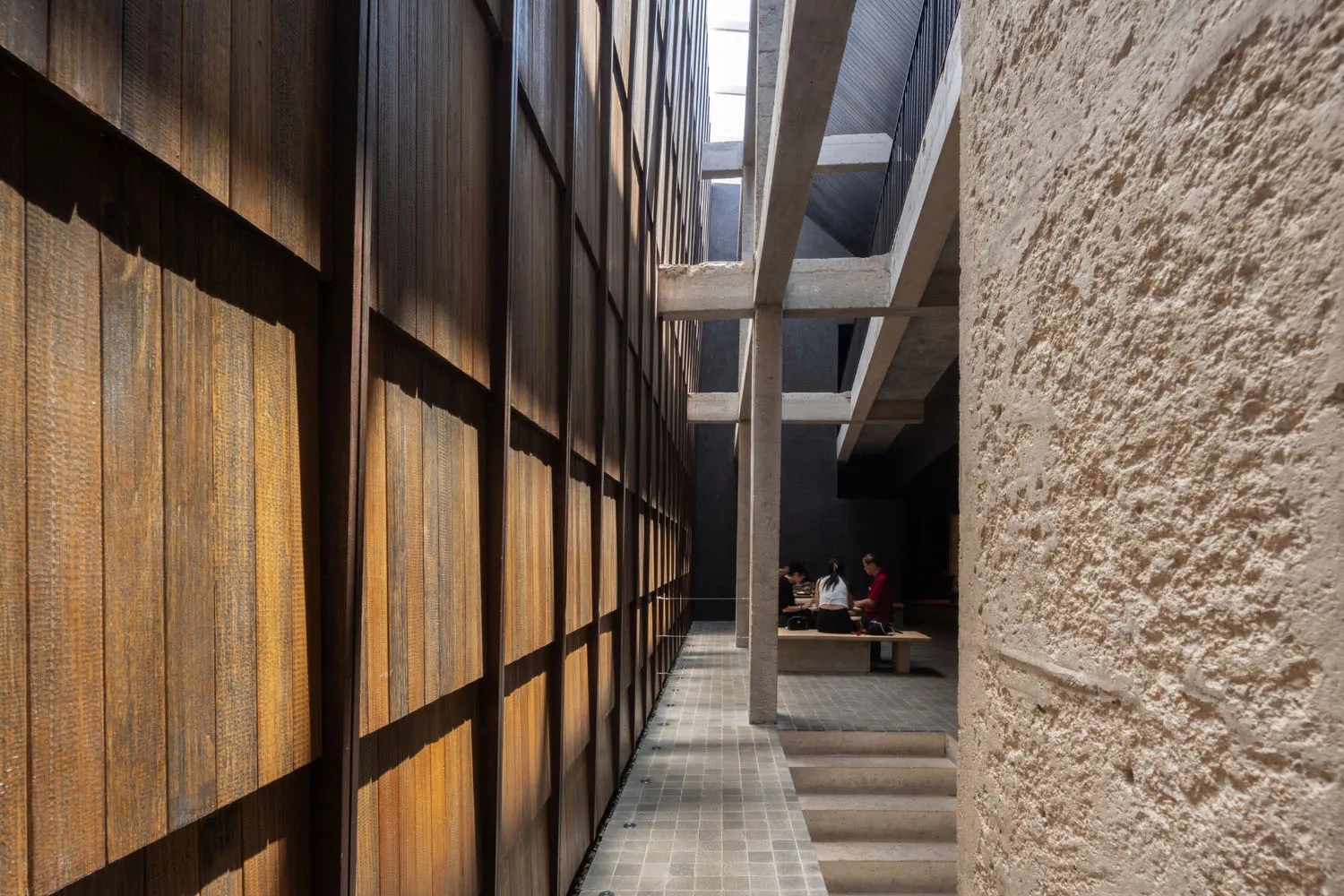 A photo of a warm and inviting hallway with wooden features, benches, and chairs, creating a cozy atmosphere for those passing through