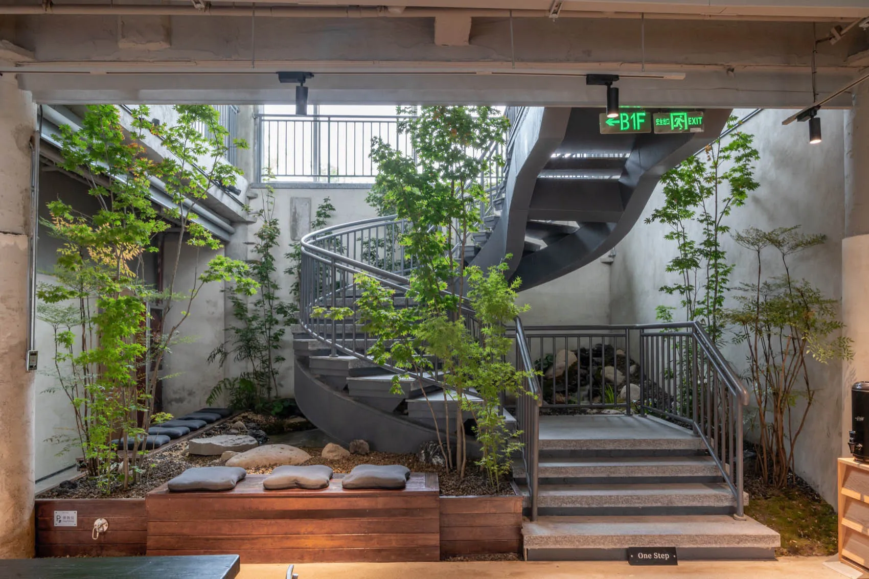 A wooden staircase with a metal railing in a hotel lobby, surrounded by potted plants adding a touch of greenery and creating a calm atmosphere