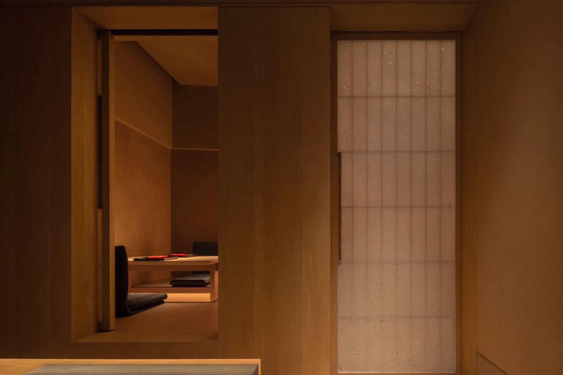 A modern living space with wooden walls and floors, featuring two couches and a chair, giving off a cozy and comfortable atmosphere