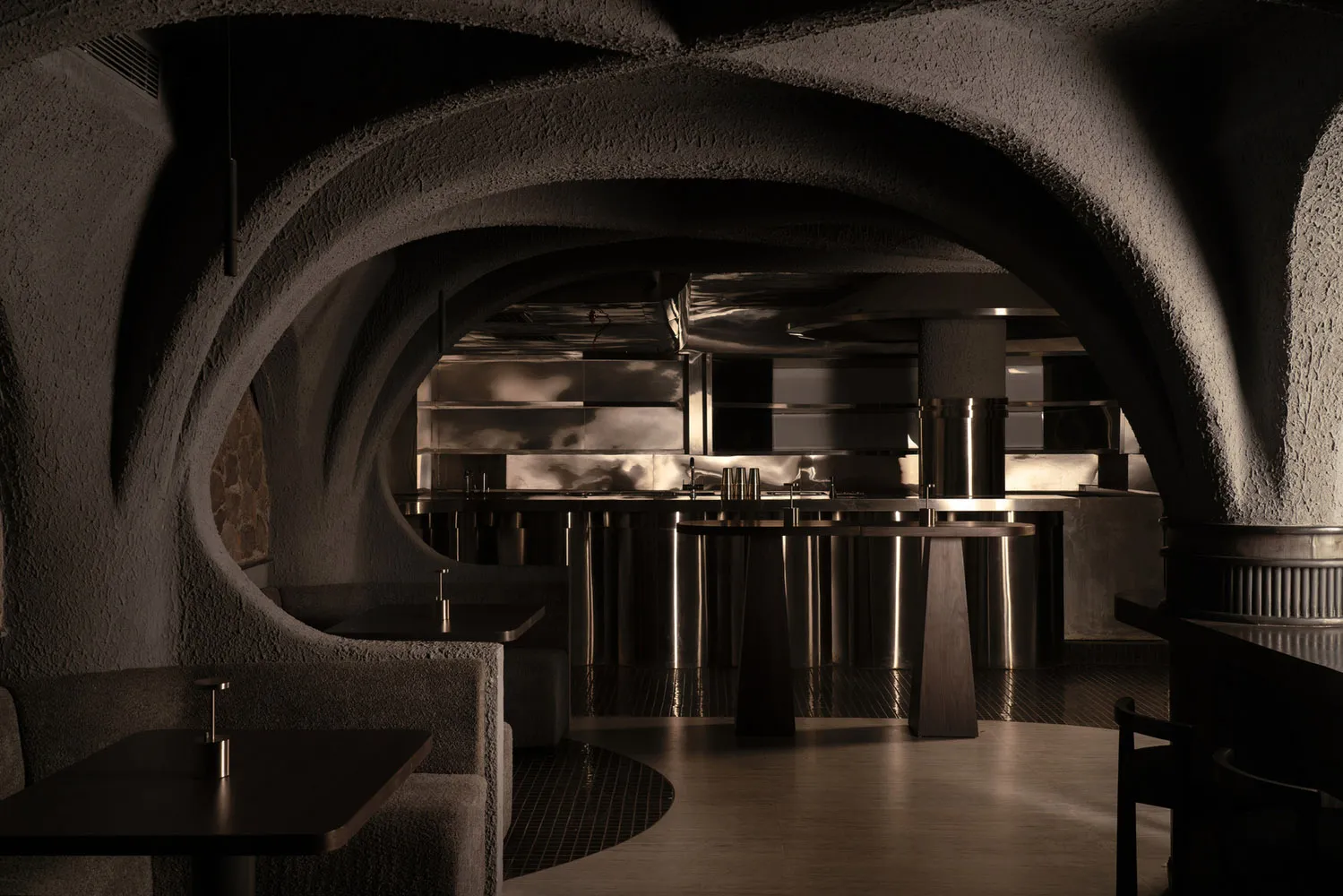 A dark and intimate bar with a circular design, central island, and chairs placed around the area for socializing and enjoying drinks