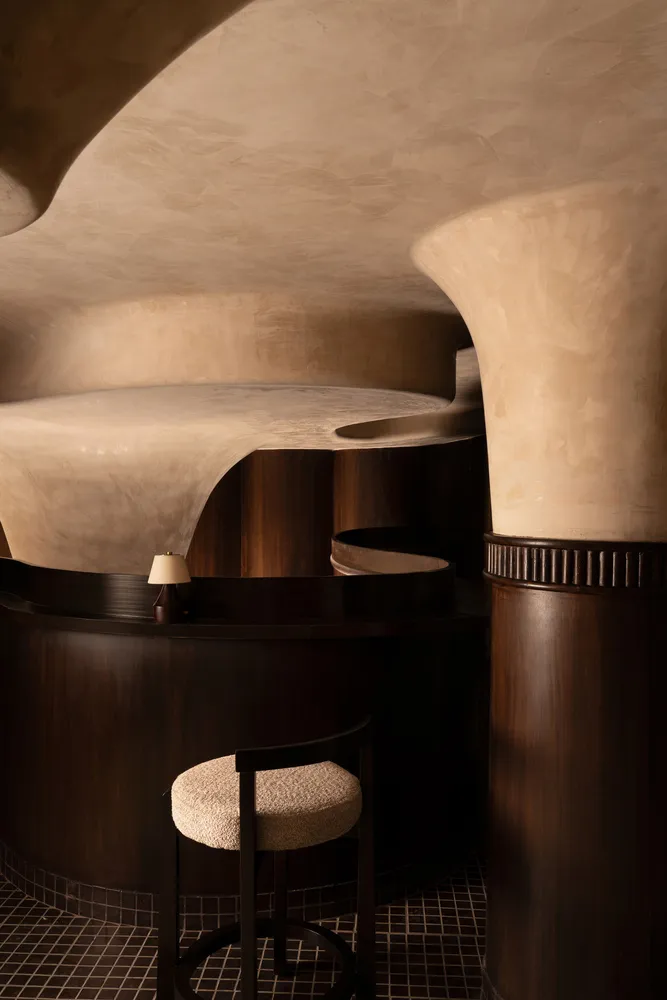 A round room with wooden panel walls, a spiral staircase, a chair, and a couch, creating a modern and cozy atmosphere