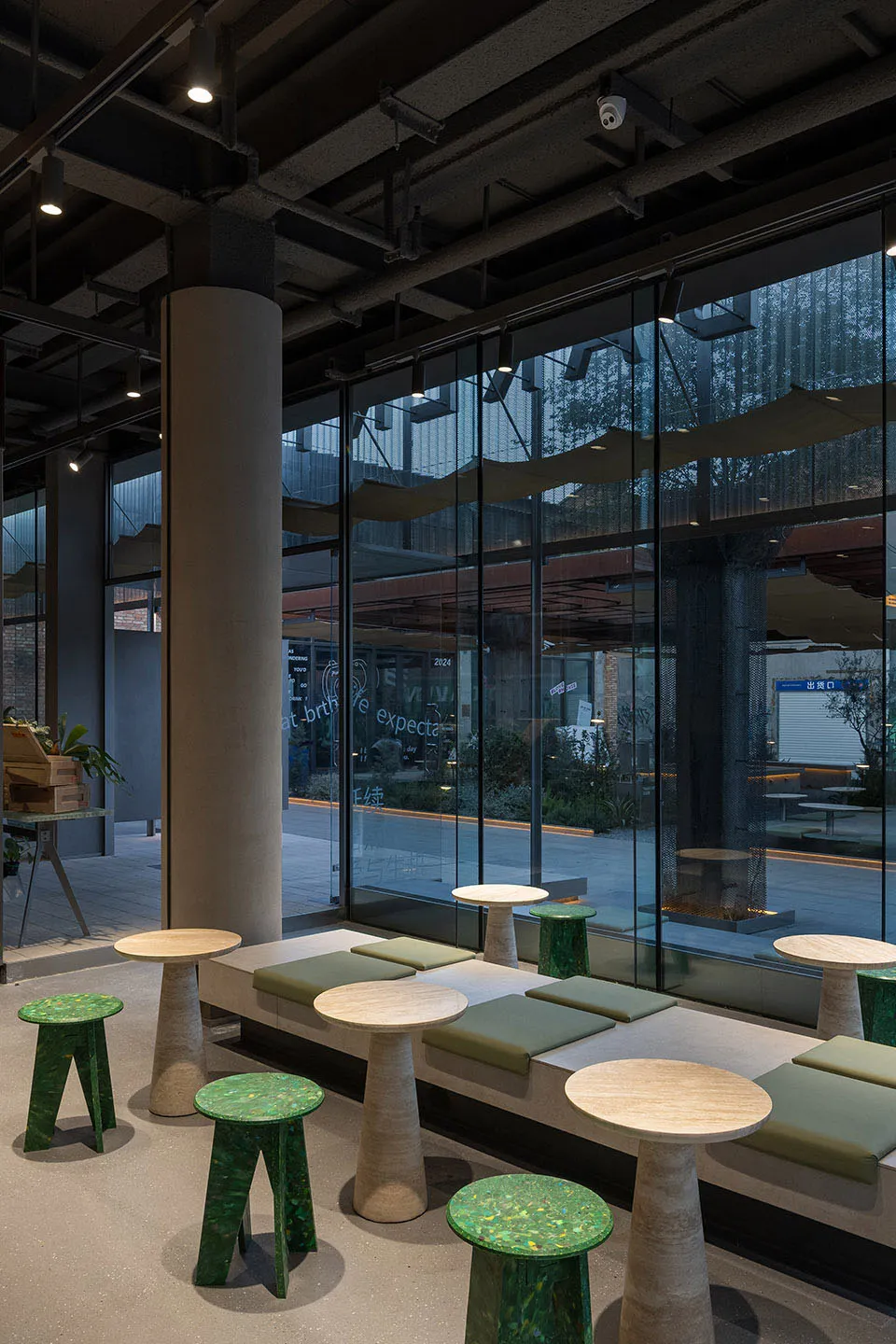 Bright restaurant interior with natural light, multiple dining tables, and green cushions