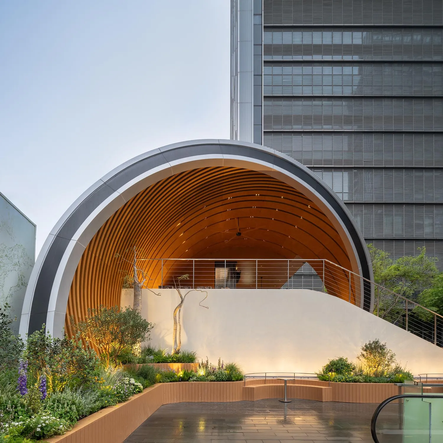 A building with a large wooden dome in front of it, surrounded by potted plants, conveying artistic expression and cultural appreciation