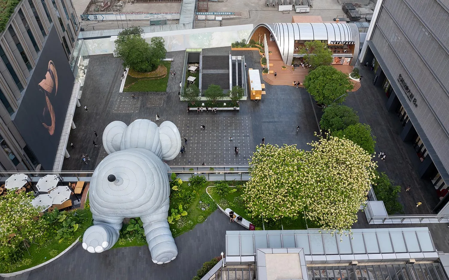 A lively art gallery with a large foam elephant sculpture as the centerpiece, surrounded by smaller elephants and people enjoying the display