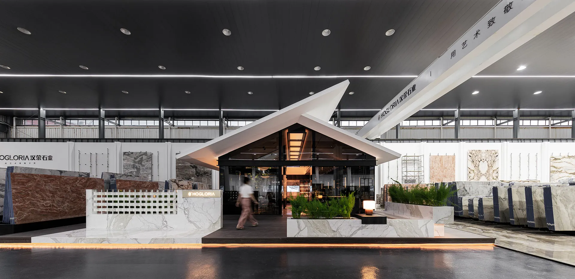 Modern building with a boat-like design, featuring a black roof, large windows, and potted plants, with two people exploring the interior