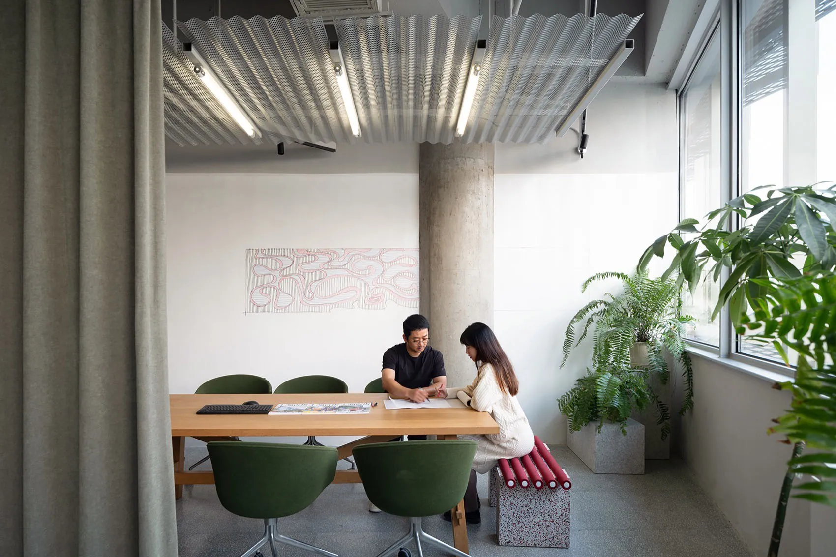 A professional office space with a table and chairs, a whiteboard wall, and two potted plants, creating a focused atmosphere