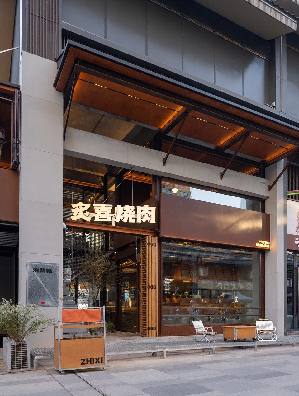 木質壁板現代亞洲餐廳，配有座椅與餐桌，大片窗戶灑入自然光線