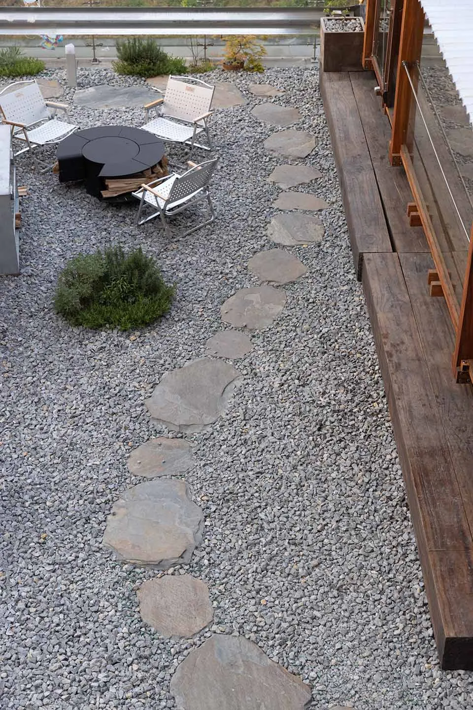 A stone walkway leads to a dining table surrounded by chairs in a relaxed outdoor seating area