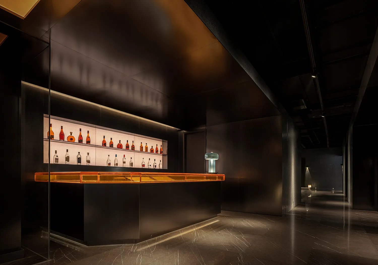 Darkly lit bar area with bottles on the countertop, creating a sophisticated atmosphere for socializing and relaxation